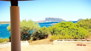 A view from a covered outdoor area with a clear blue sea and distant mountains. - Villa Twin (Golfo Aranci)