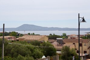 A coastal town with terracotta-roofed buildings, a street lamp, and a mountain in the background. - Casa Gabriella (Olbia)