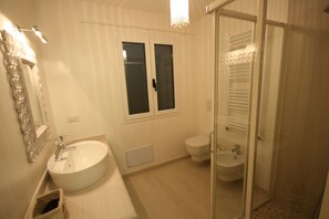 A bathroom with a large sink, a toilet, and a glass-enclosed shower. - Casa Mirella (Golfo Aranci)