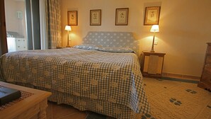 Un dormitorio con colcha a cuadros, dos lámparas de noche y cuadros enmarcados en la pared.