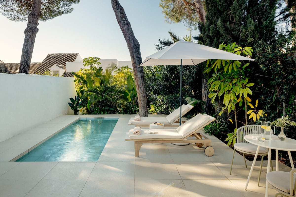 A poolside area with lounge chairs, a table, and an umbrella.