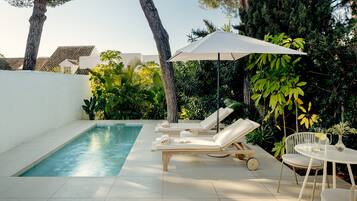 A poolside area with lounge chairs, a table, and an umbrella.