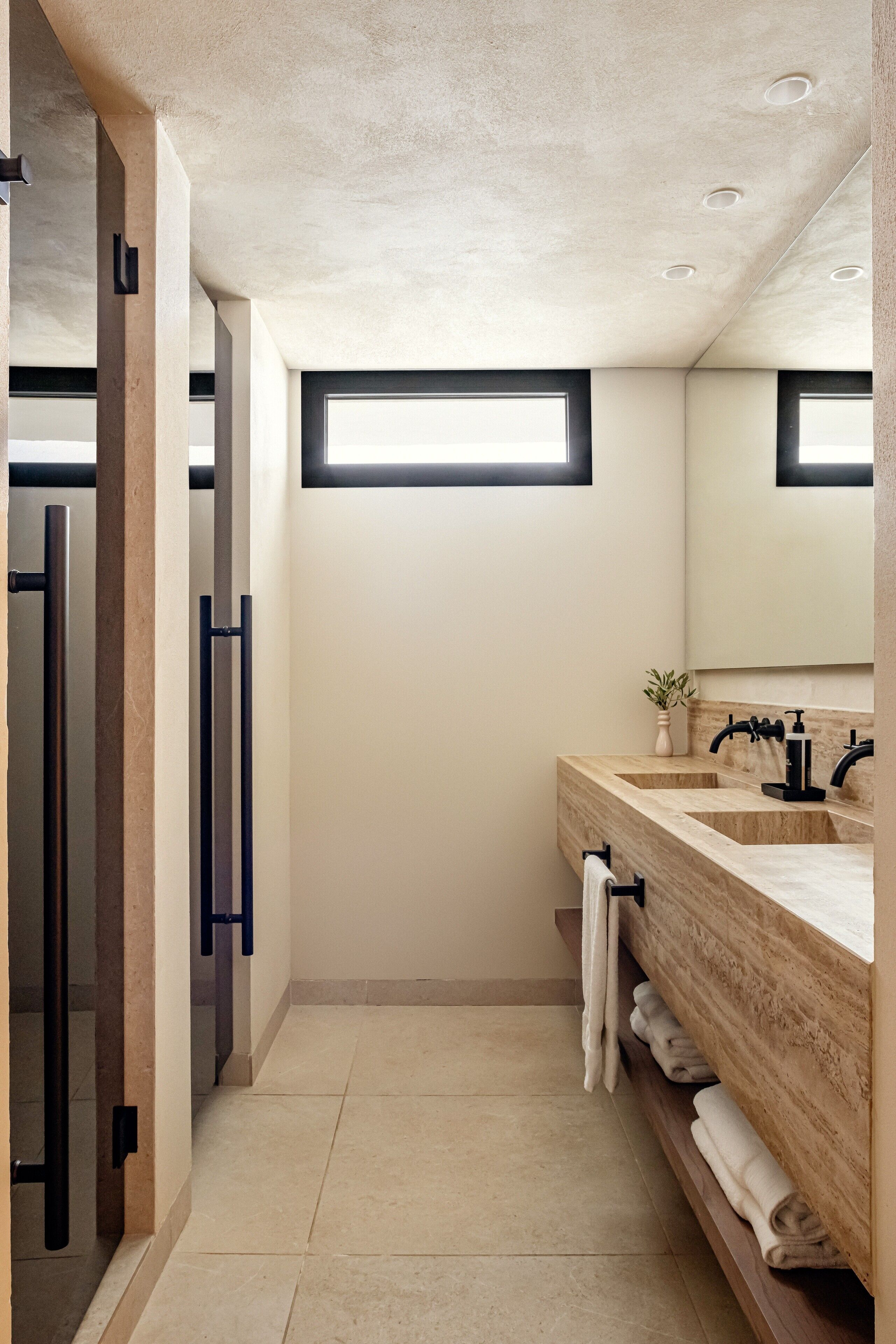 Une salle de bain moderne avec un grand miroir, deux lavabos et une fenêtre.