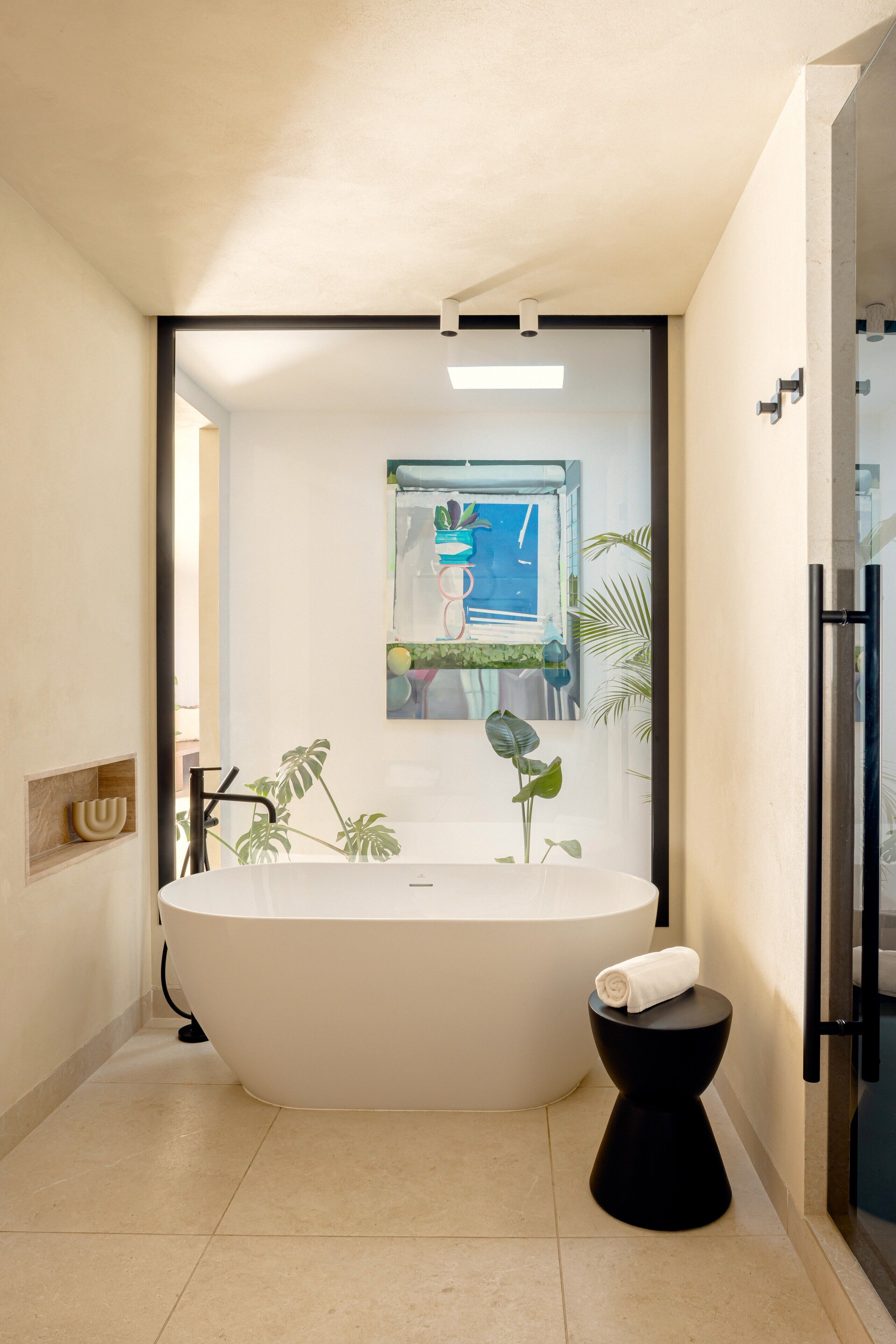 Een moderne badkamer met een vrijstaand bad, een zwart toilet en een kleine plant.