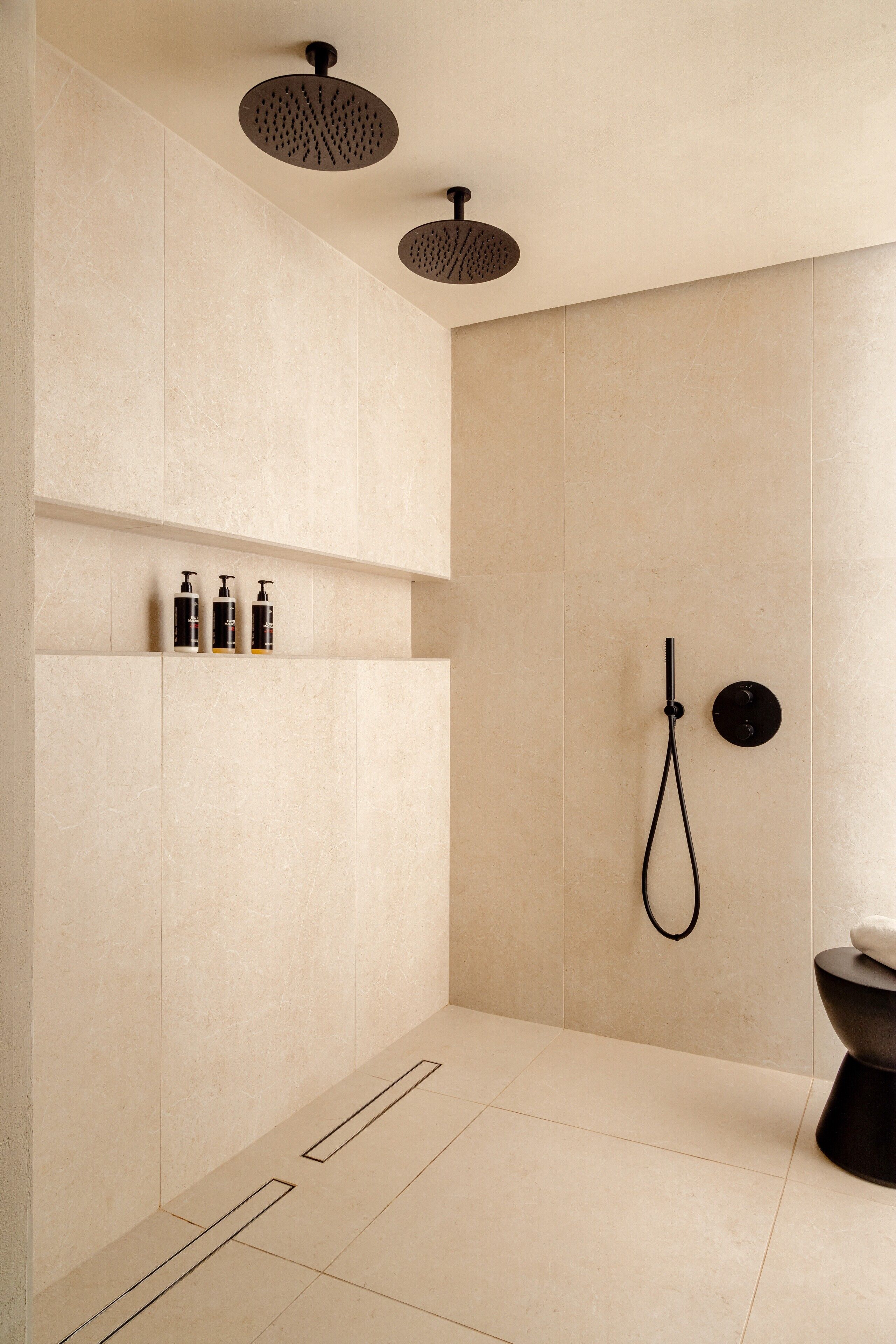 A modern bathroom with a shower, toilet, and shelf with toiletries.