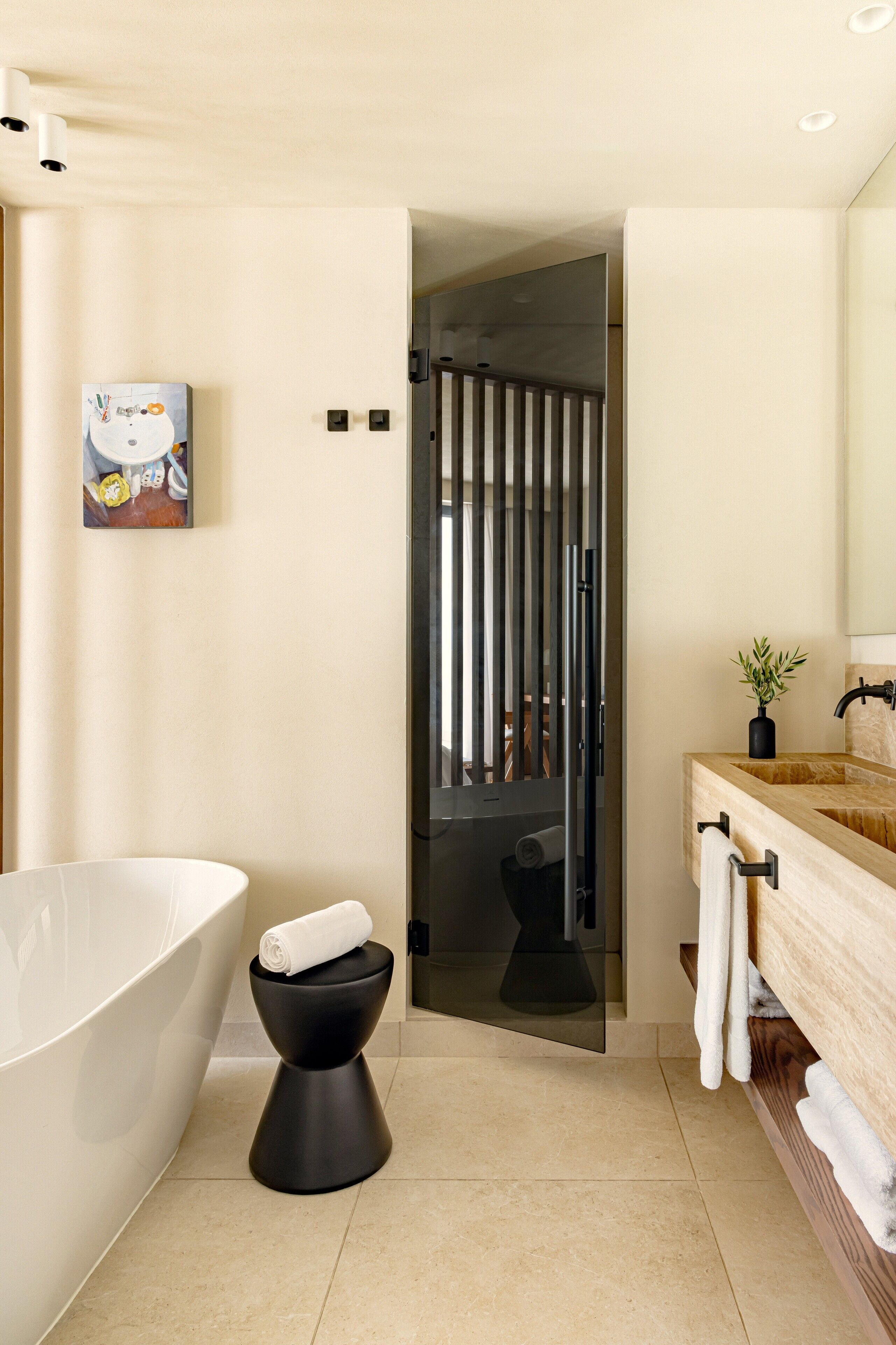 A modern bathroom with a freestanding bathtub, a black toilet, and a wooden vanity with a mirror.