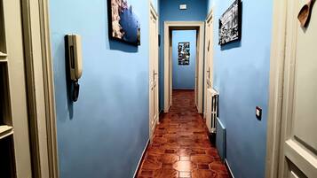 Un pasillo con paredes azules, suelo de madera y una puerta al final.