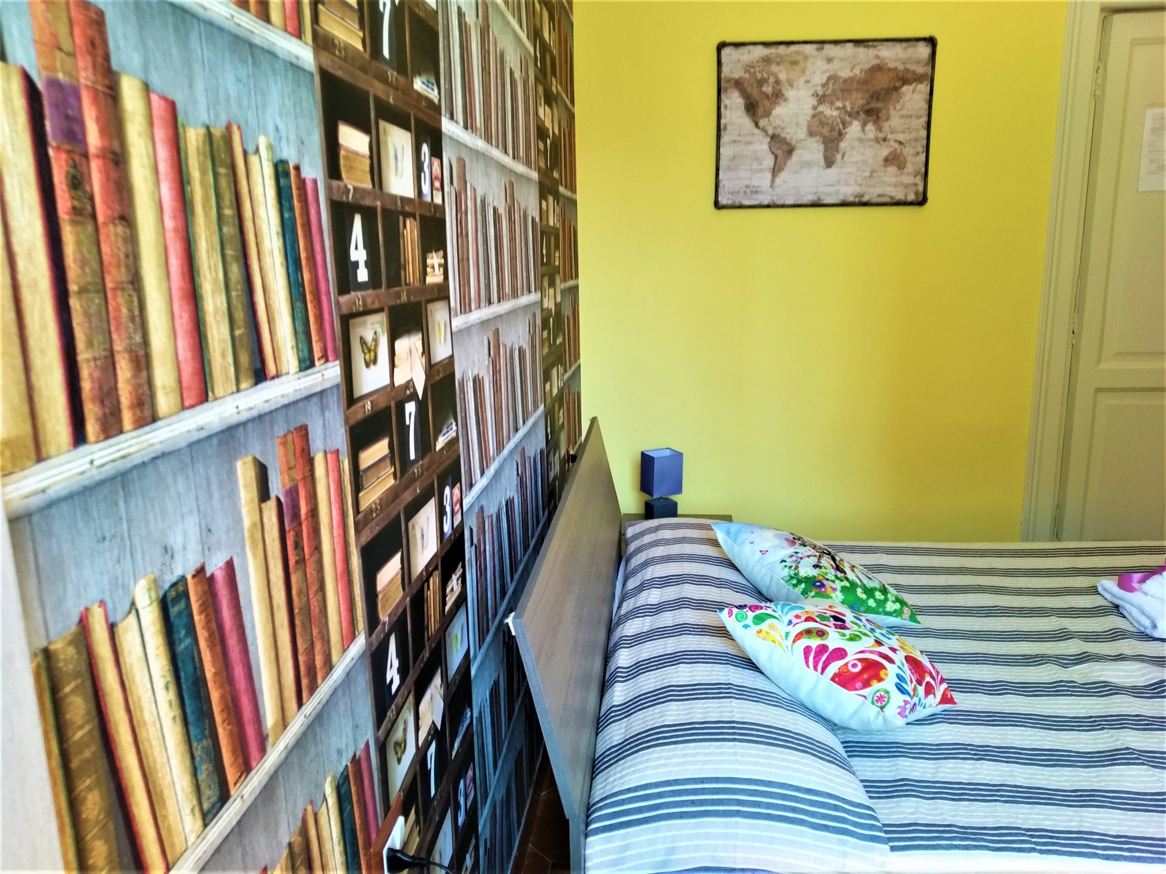 A room with a bed, a bookshelf, and a world map on the wall.