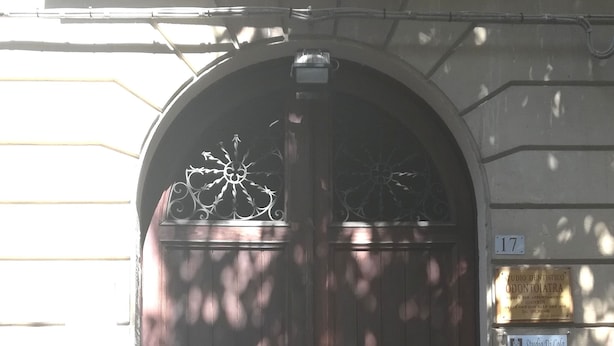 A dark wooden double door with a decorative metal crest above it, set in a stone wall. - B&B Il Poeta (Palermo)