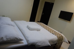A hotel room with a bed, a TV mounted on the wall, and a door. - Mannra Hotel (Manila)