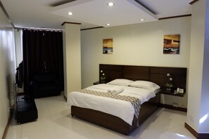 A hotel room with a large bed, a bedside table with a phone, and a small plant. - Mannra Hotel (Manila)