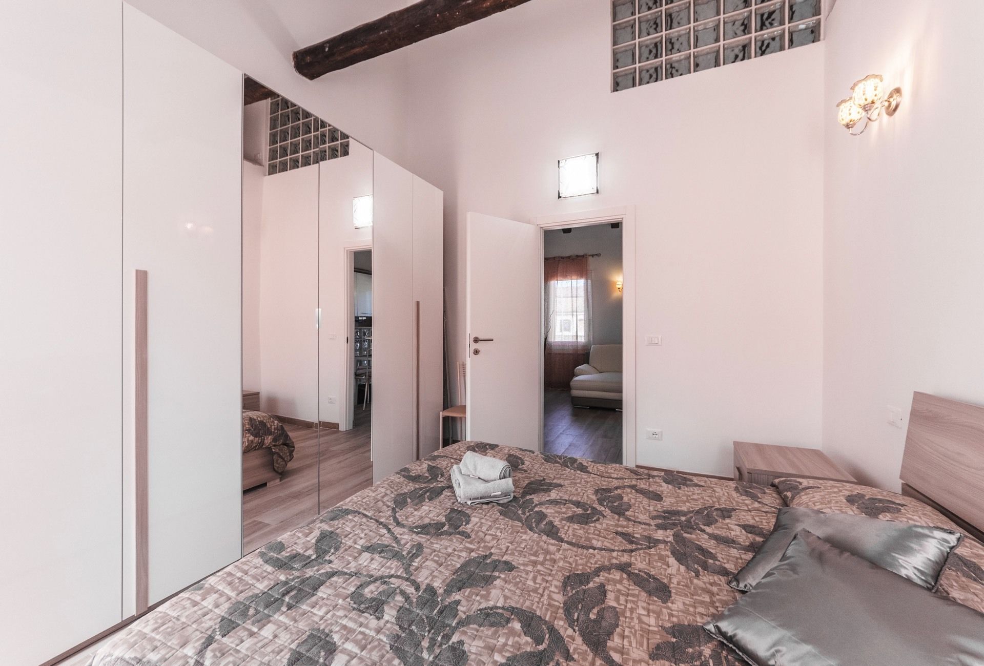 Un dormitorio con una cama grande, un armario y vistas a una sala de estar.