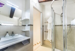 Une salle de bain moderne avec un lavabo blanc, un miroir et une douche.