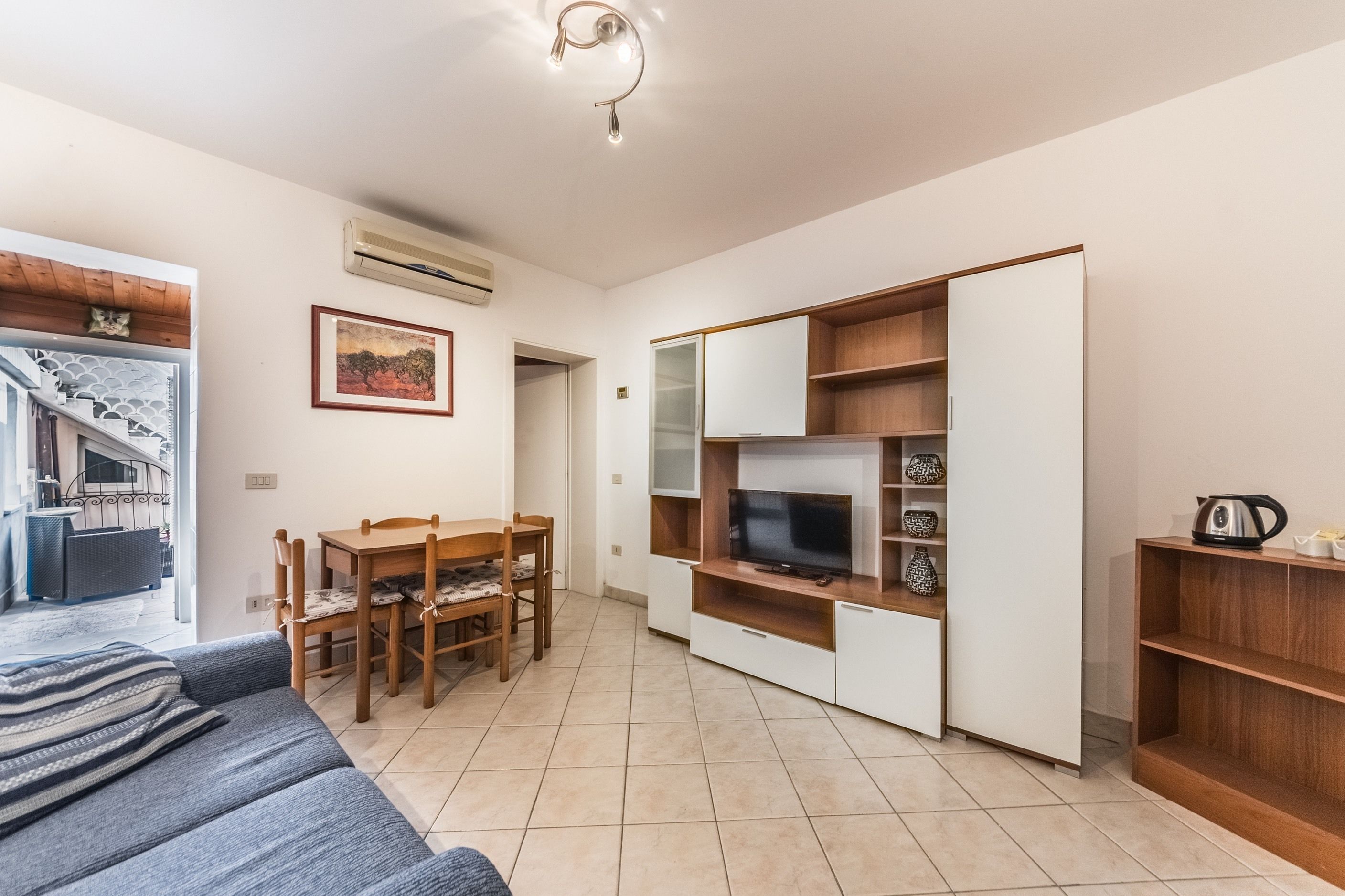 A compact living space with a sofa, a dining table, a TV, and a wardrobe.