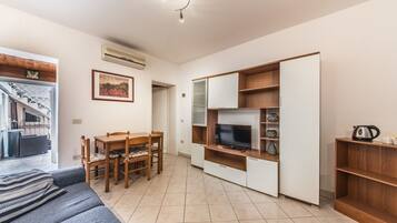 A compact living space with a sofa, a dining table, a TV, and a wardrobe.
