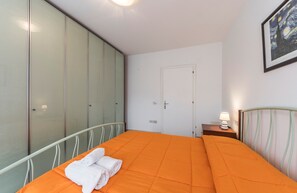 Une chambre à coucher avec un grand lit, une armoire, une porte et une table de chevet avec une lampe.
