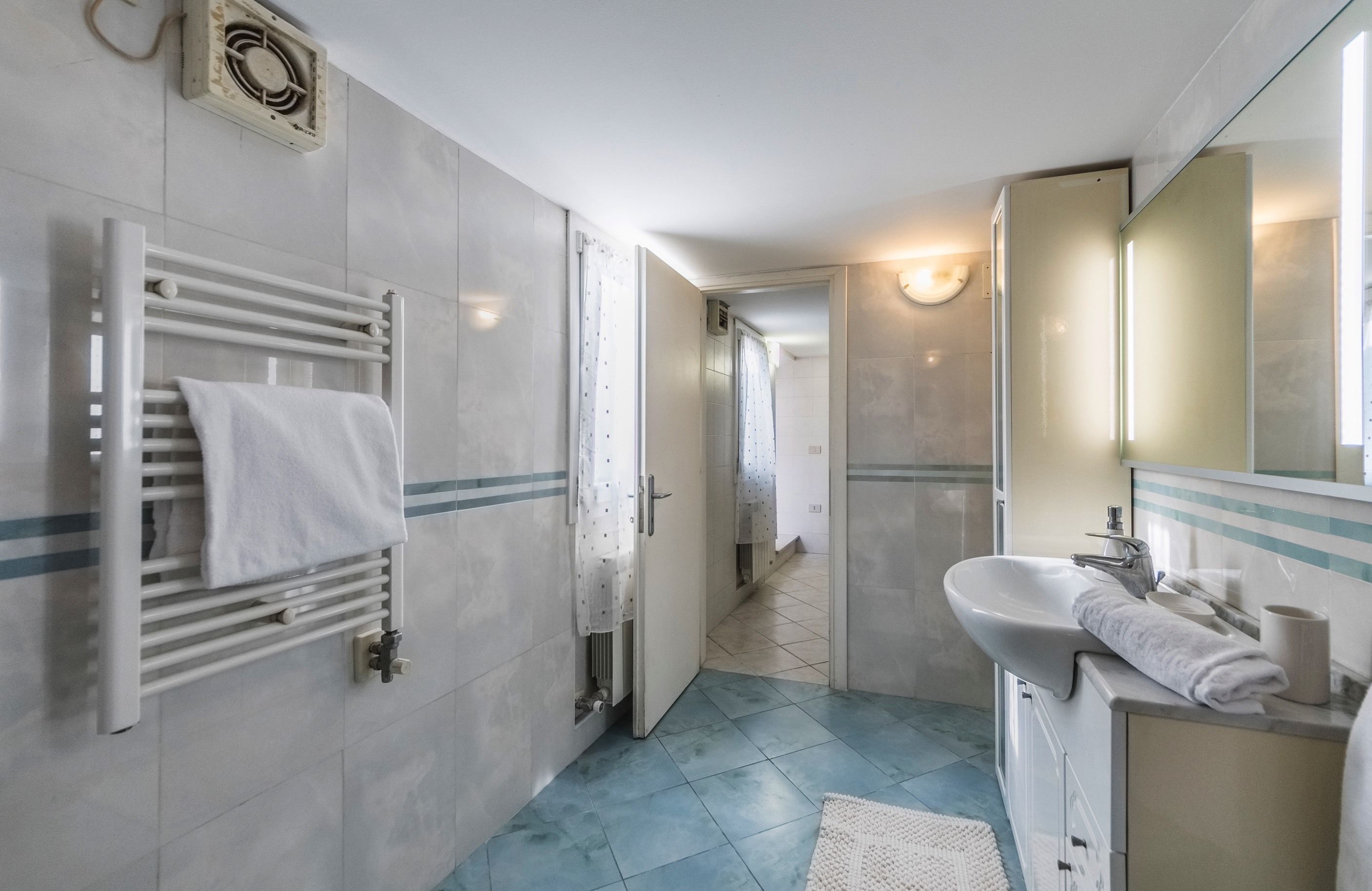 A modern bathroom with a white sink, mirror, and towel rack.