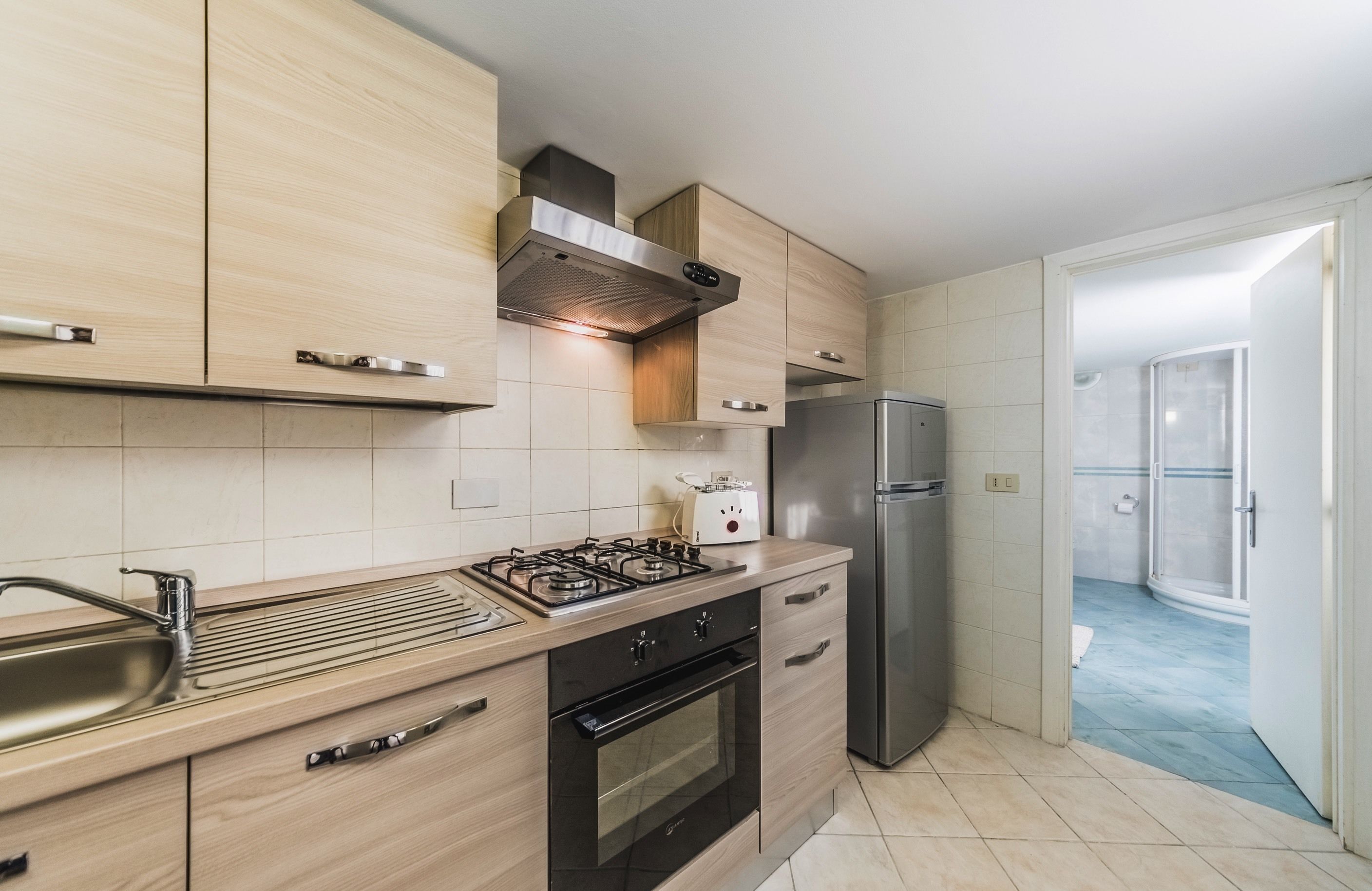 Une cuisine moderne avec des meubles en bois, une cuisinière à gaz, un four encastré et un réfrigérateur en acier inoxydable.