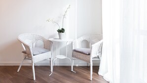 A room with two white wicker chairs, a small white table, and a potted orchid. - Quattro Canti Charming Flat (Palermo)
