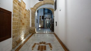 A marble corridor with a coat of arms and the text "PALAZZO MONCADA" leading to a glass door entrance. - Quattro Canti Charming Flat (Palermo)