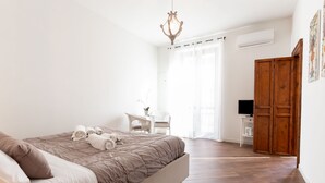 A bedroom with a large bed, a television, a wooden wardrobe, and a desk with a chair. - Quattro Canti Charming Flat (Palermo)