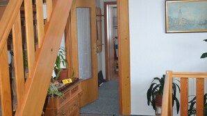 Una escalera de madera que lleva a un rellano con vista a una pintura de un paisaje urbano.