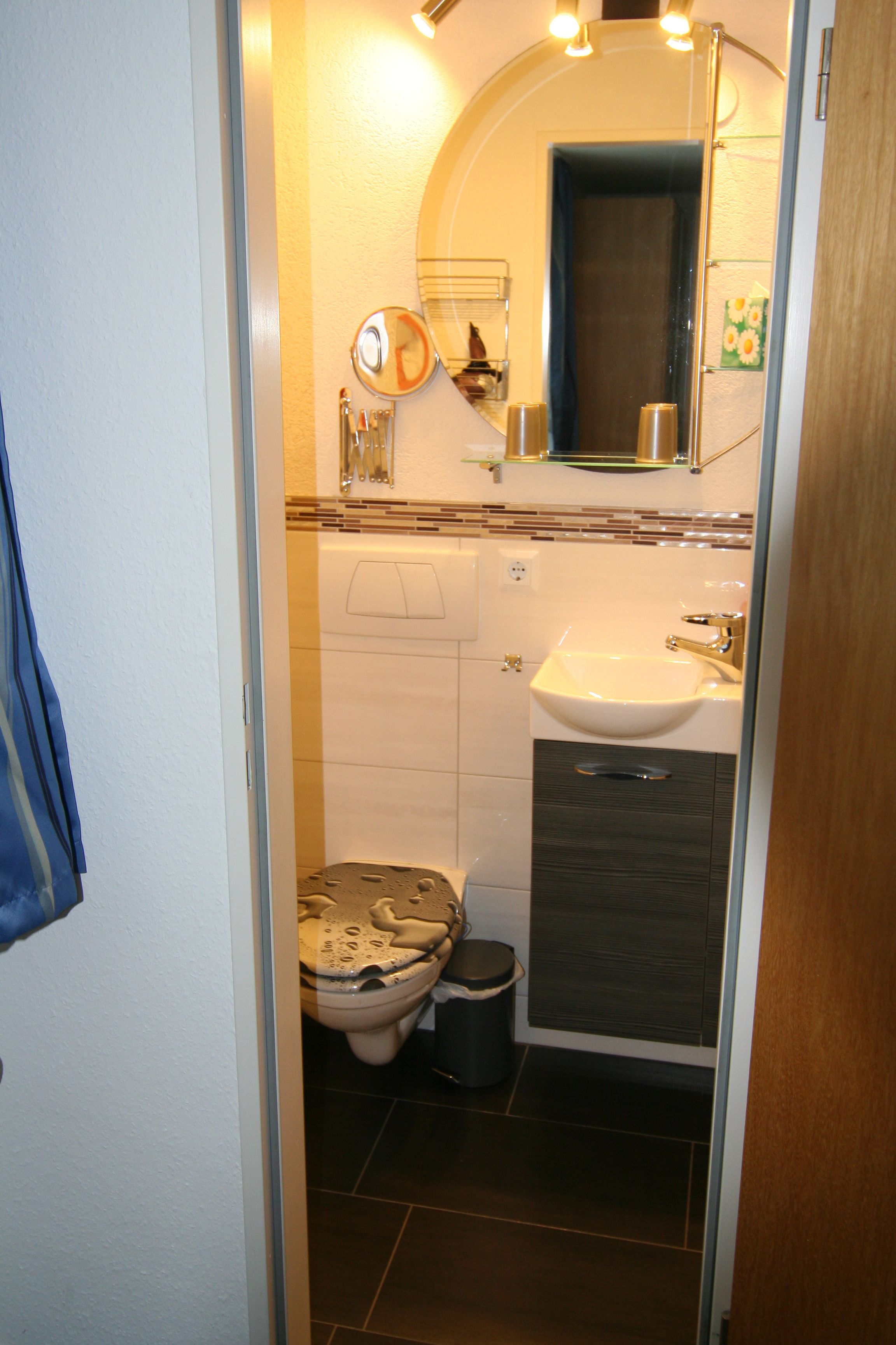 Un baño con inodoro, lavamanos y espejo.