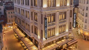 Un hotel de varios pisos con un estilo arquitectónico clásico, que cuenta con grandes ventanales y una entrada destacada.