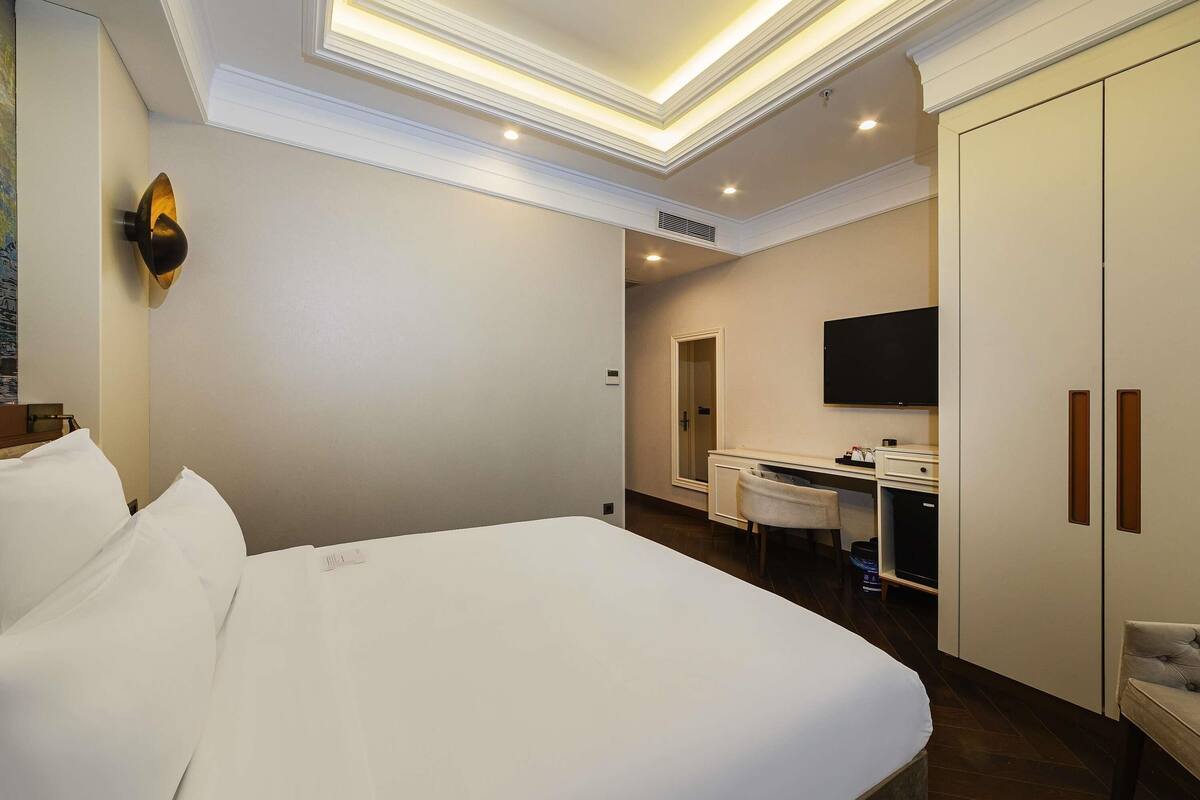 Ein Hotelzimmer mit einem Bett, einem Schreibtisch, einem Fernseher und einem Kleiderschrank.
