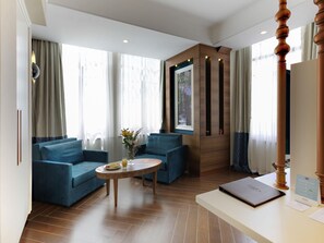 A hotel room with a blue sofa, a round wooden table, and a large window with curtains. - Mercure Istanbul Sirkeci (Istanbul)