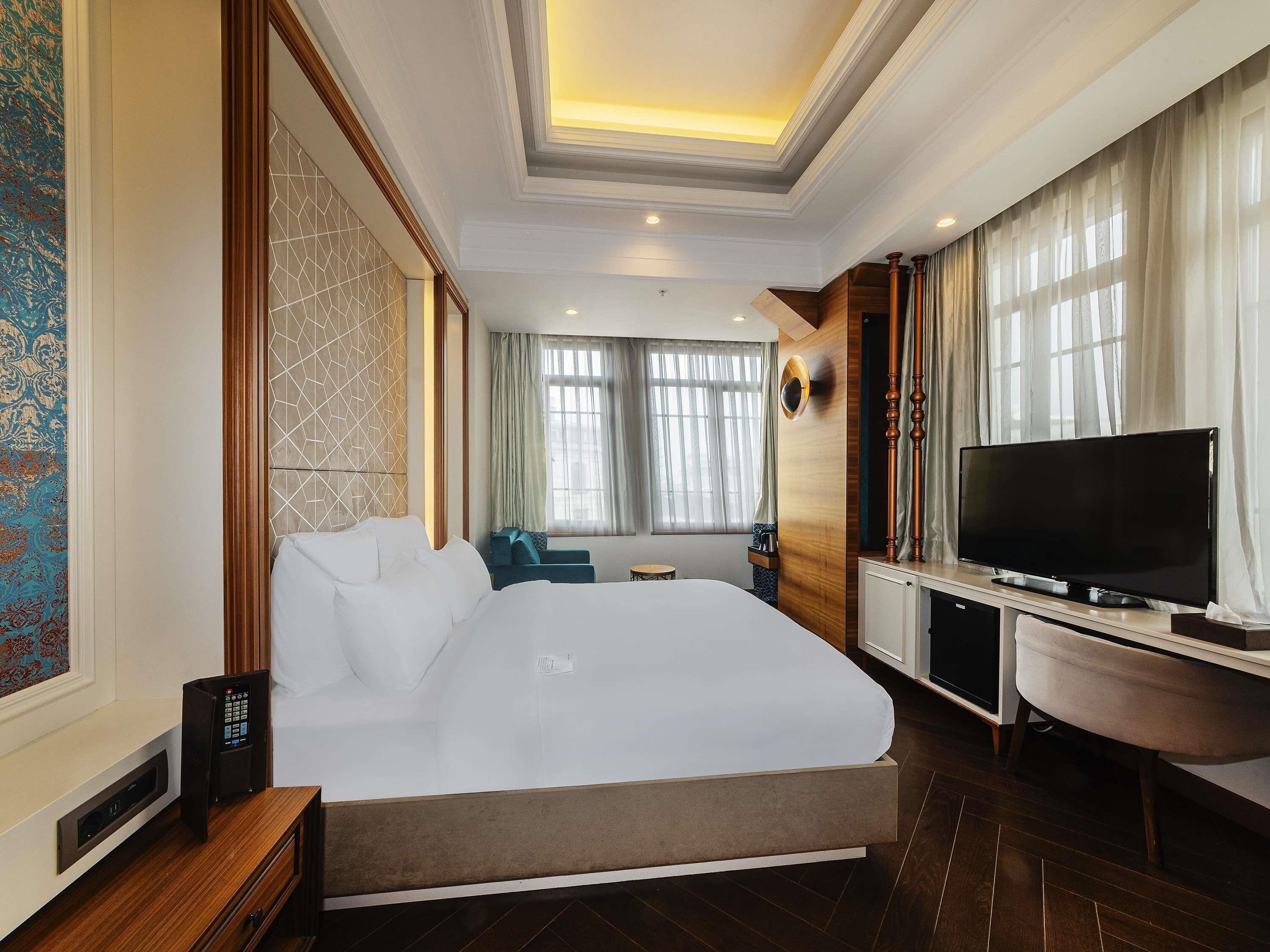 Habitación de hotel con una cama grande, un televisor de pantalla plana, un escritorio y una silla.