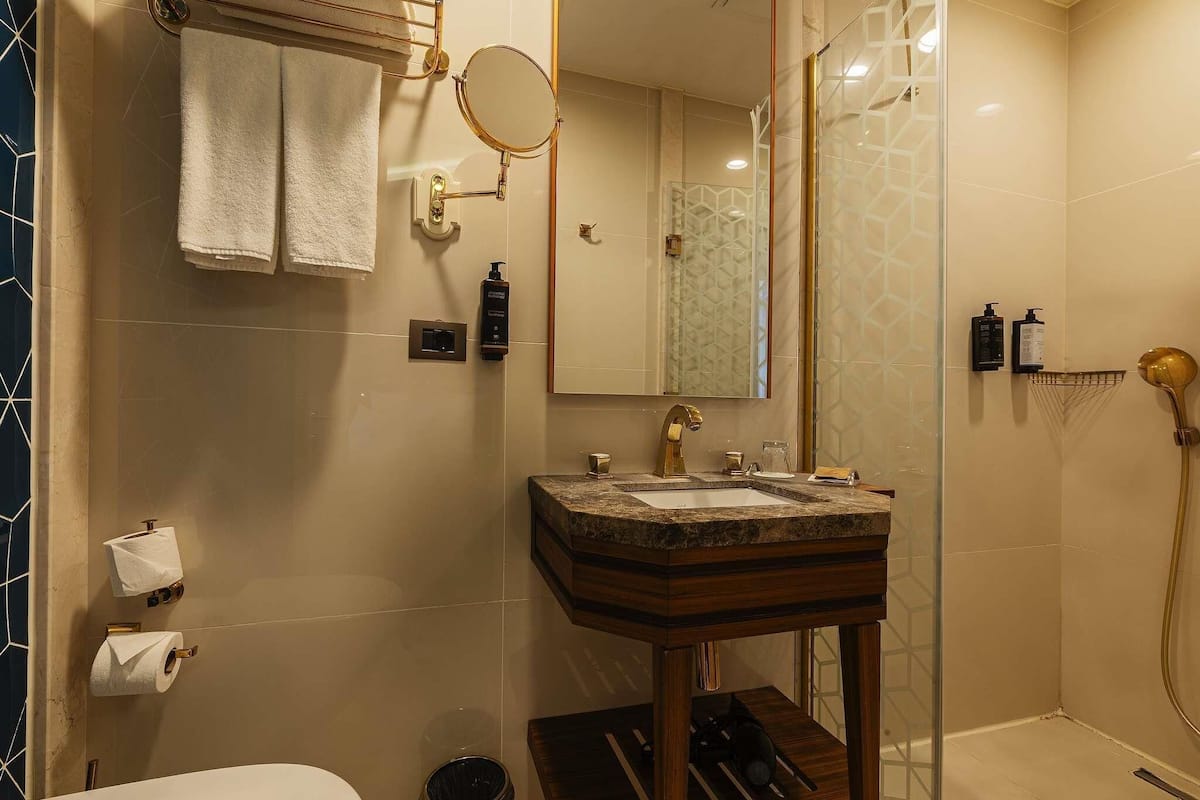 Une salle de bain avec un lavabo en marbre, un miroir, un porte-serviettes et une douche.