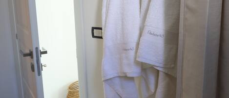 A bathroom with a white bench, a wooden towel rack, and a basket on the floor.