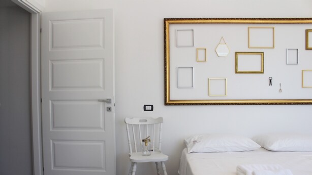 Een hotelkamer met een bed, een stoel en een muur met ingelijste foto's.