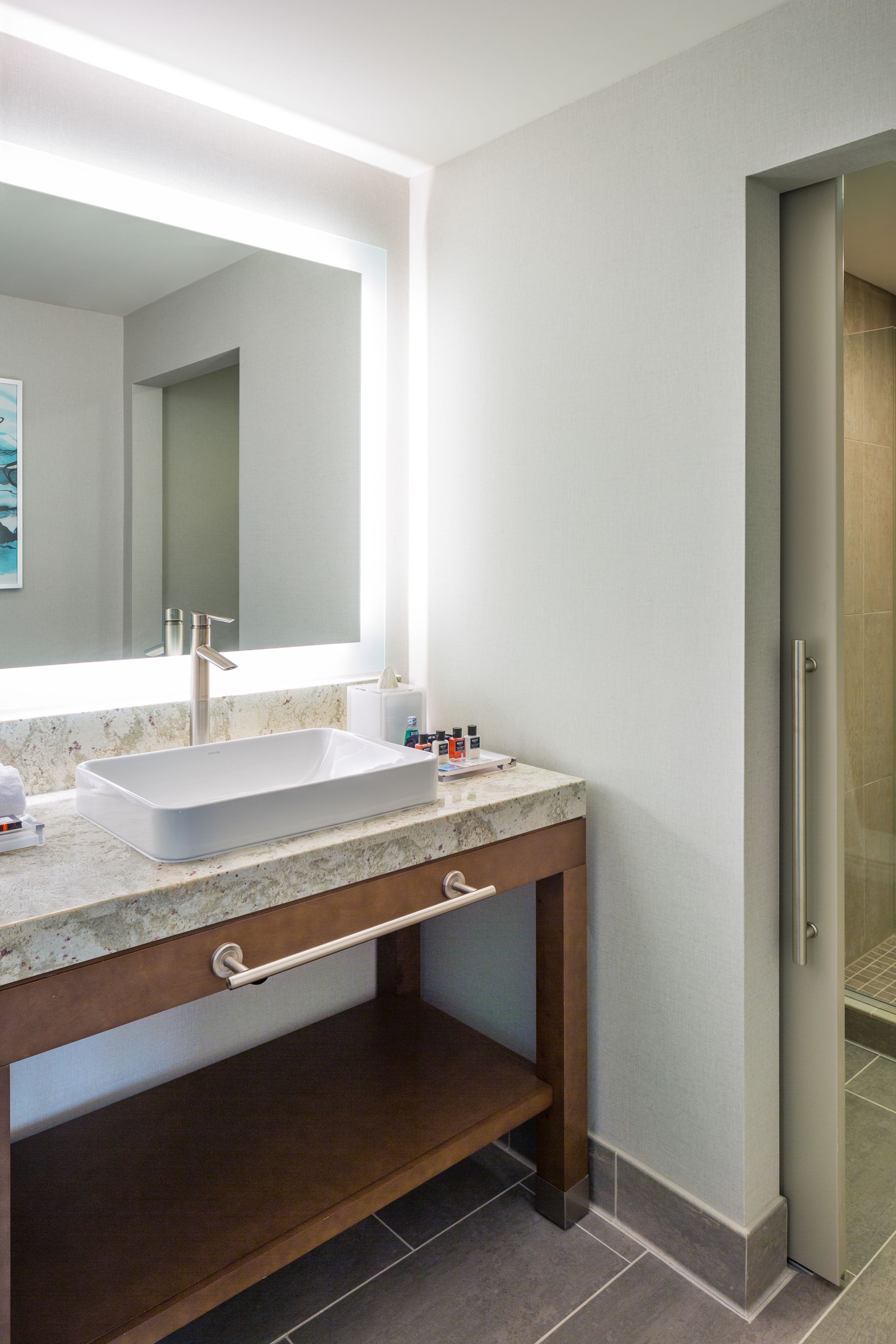 A modern bathroom with a rectangular sink, a large mirror, and a shower door.