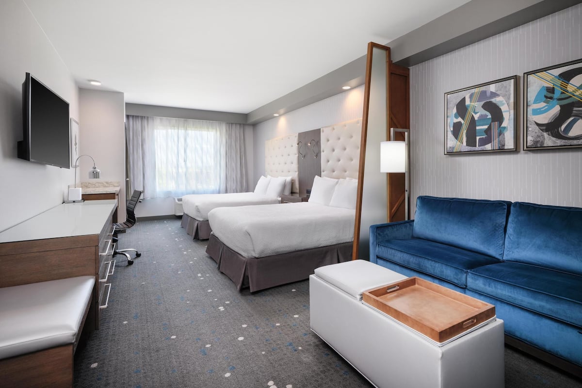 Una habitación de hotel con cama, sofá, escritorio y televisor.