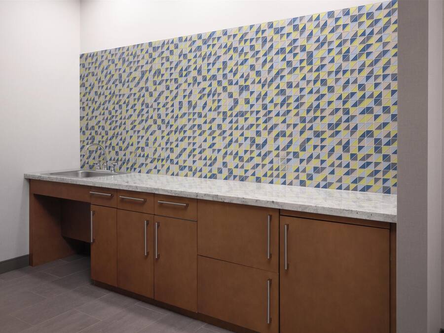 A kitchen with a patterned backsplash, wooden cabinets, and a countertop.