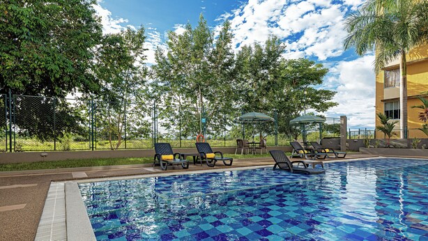 A swimming pool with a checkered pattern, surrounded by lounge chairs and a covered seating area.