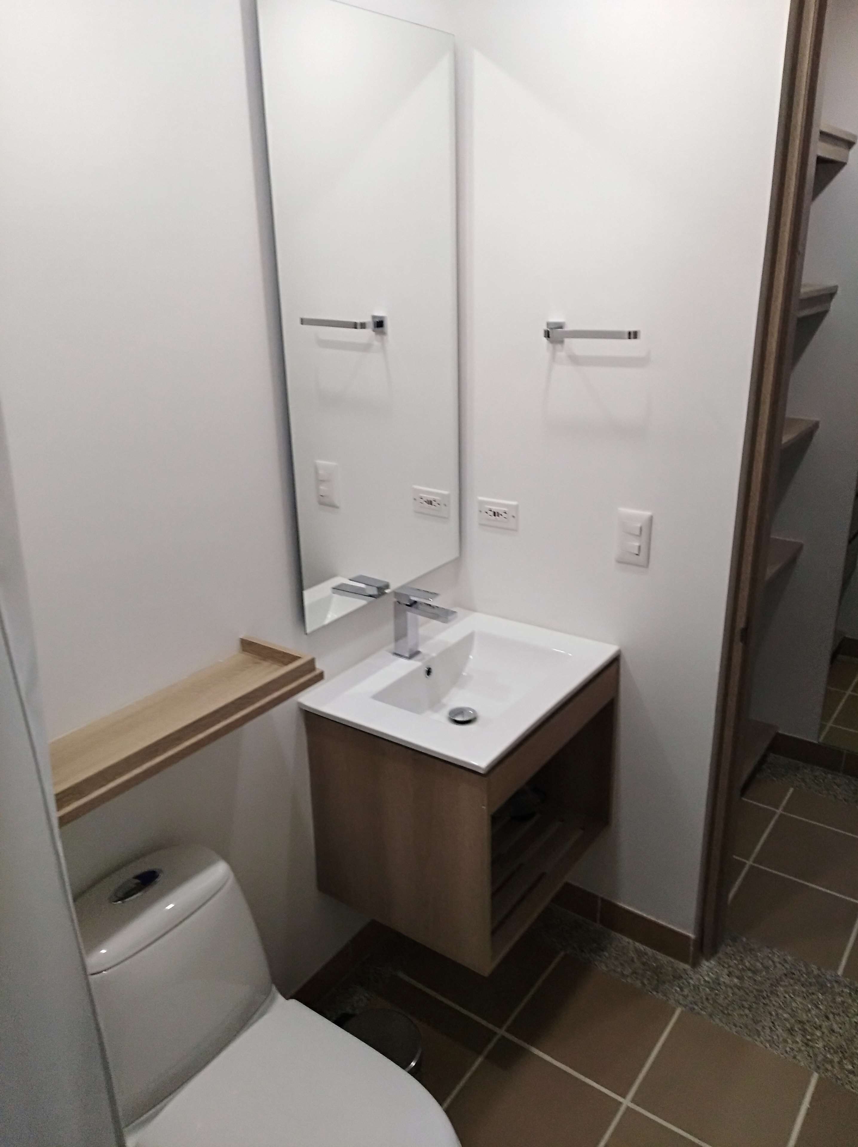 Un baño pequeño con lavamanos blanco, un espejo y un inodoro.