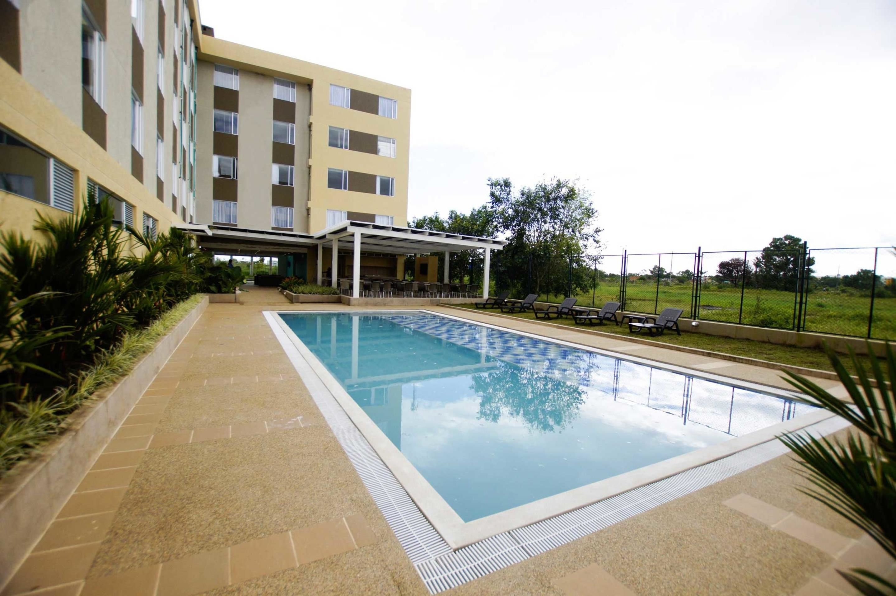 A swimming pool with a covered seating area, surrounded by a building with multiple balconies.