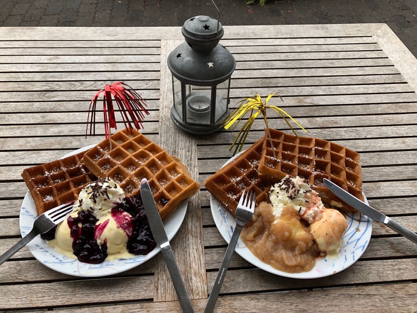 Due piatti di waffle con condimenti su un tavolo di legno.