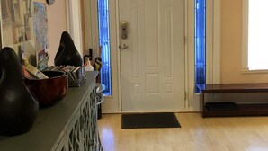 Une pièce avec une porte blanche, un banc noir, une carte accrochée au mur et un paillasson noir à l’entrée.
