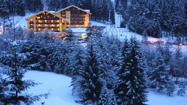 A snow-covered lodge with multiple balconies and a ski lift in the background. - Family & Wellness Hotel Shandranj (Tesero)