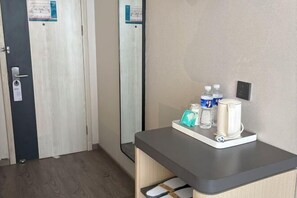 A hotel room with a wooden floor, a desk with a tray holding toiletries, and a mirror on the wall. - Jinjiang Inn Huai'an Development Zone (Huai'an)