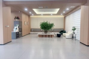 Een moderne receptie met een zithoek, een receptiebalie en een kamerplant.