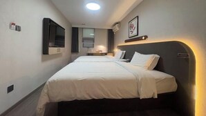 Ein Hotelzimmer mit zwei Betten, einem Fernseher, einem Spiegel und einem gerahmten Bild an der Wand.