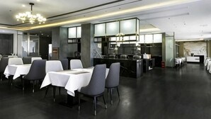 Un restaurant moderne avec des tables et des chaises, un espace cuisine et un bar.