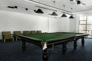 Una mesa de billar con sillas alrededor, una ventana con vistas y un techo con luces.