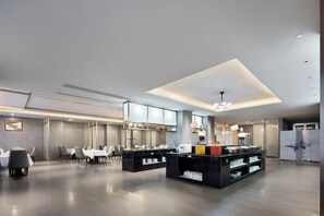 Un hall d’hôtel moderne comprenant un comptoir d’accueil, un espace salon et un grand espace ouvert.