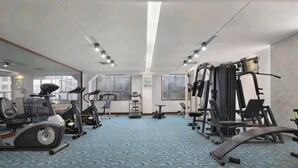 Un gimnasio con equipo de ejercicio, ventanas amplias y un suelo azul con estampado.